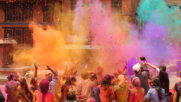 A group of people celebrating the Holi Festival in India, with colored powder flowing through the air