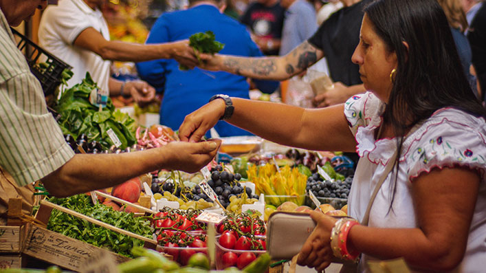 People buying fruit and vegetables at a street market