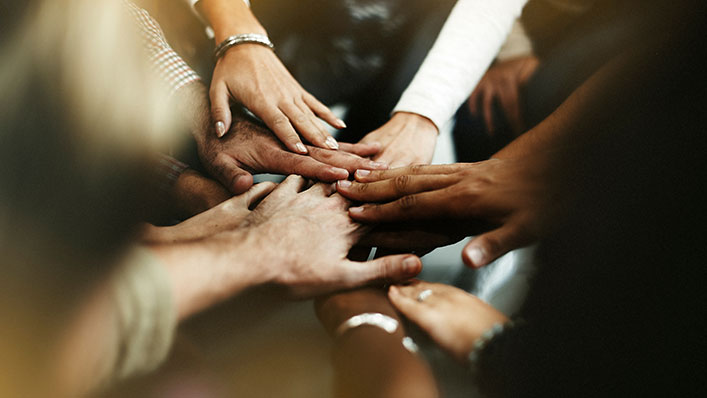 A group of diverse peoples' hands stacking on top of each other