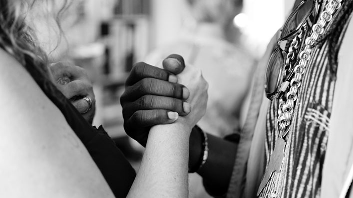 Two hands, one white and one black, coming together in a powerful handshake