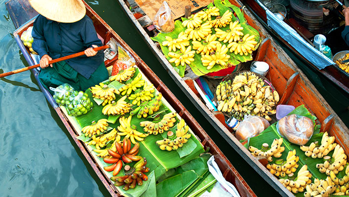 A person selling fruit on a small boat on the river