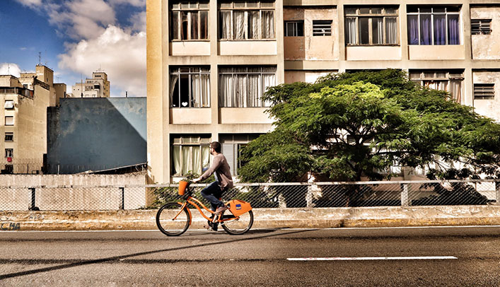 A man riding a bike on a empty street with apartments in foreground