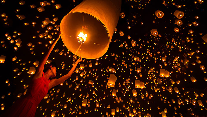 A night sky full of beautiful floating paper lanterns illuminated by flames