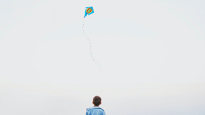 A boy flying a kite alone