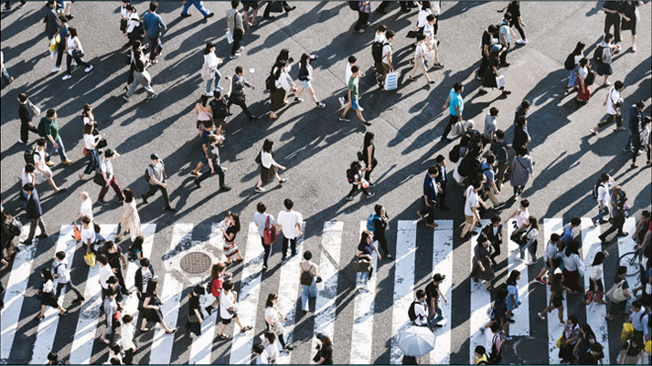 Many people walking in separate directoins across a zebra line on a busy street