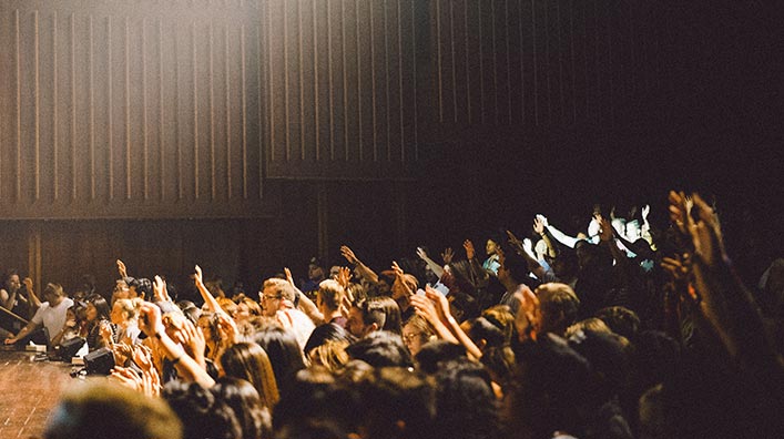 A group of people raising their hands on an auditorium